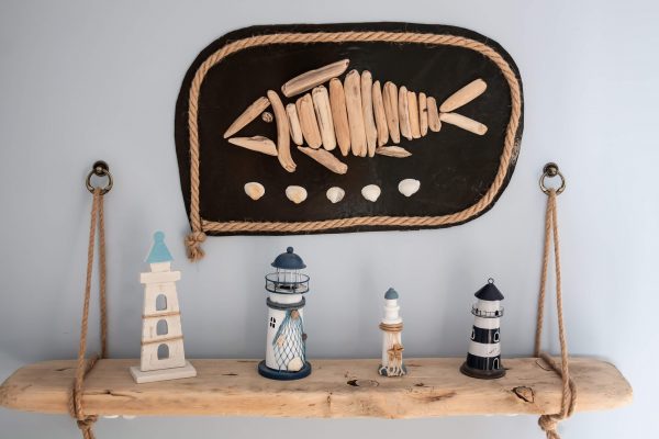 Lighthouse souvenirs on wooden shelf with ocean art and ship rope support local
