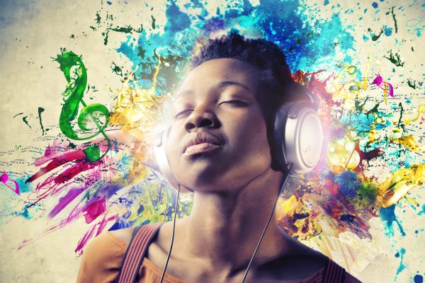 Young black woman with eyes closed, enjoying listening to music through headphones