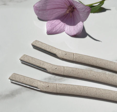 Wildpier biodegradable dermaplaning blade razors with flower in background. Natural Exfoliation